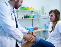 Male doctor examining patients knee