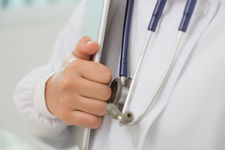 Photo d'un docteur qui tient dans sa main des documents médicaux